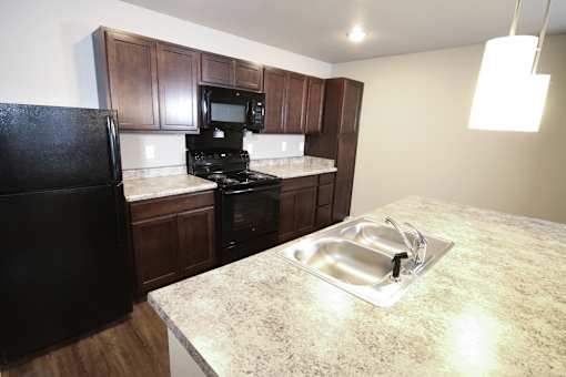 A kitchen with a black fridge, microwave, and oven.