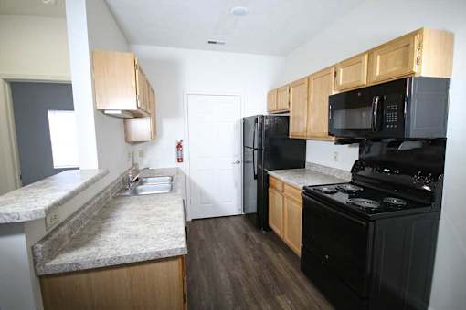 A kitchen with black appliances and wooden cabinets.