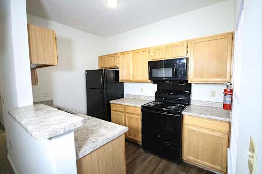 A kitchen with black appliances and wooden cabinets.