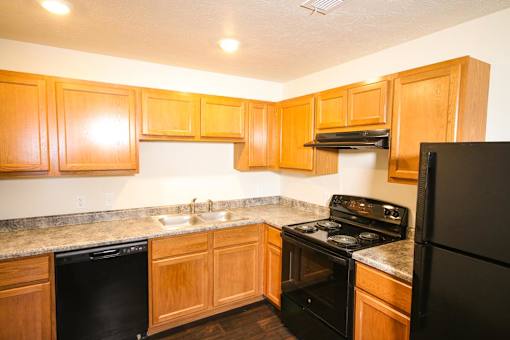 A kitchen with black appliances and wooden cabinets.