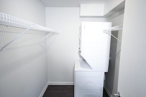 A white closet with a white dresser and a white closet rod.