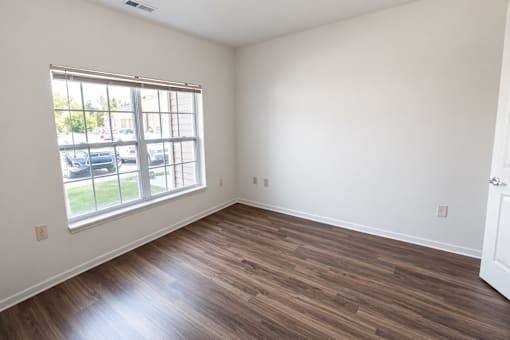 A room with a window and wooden flooring.