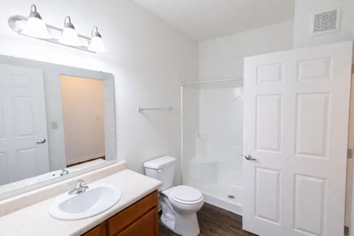 A white bathroom with a toilet, sink, and mirror.