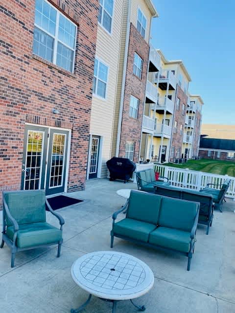 A patio with a table, two chairs and a couch.