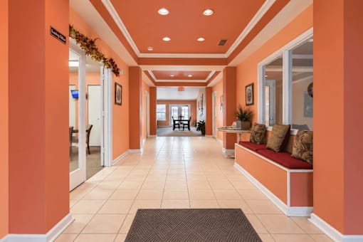 A hallway with orange walls and a bench with pillows.