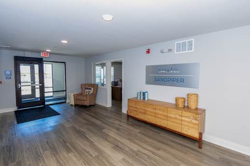 A wooden bench with baskets on top sits in a room with a sign that reads "SANDPIPER.".