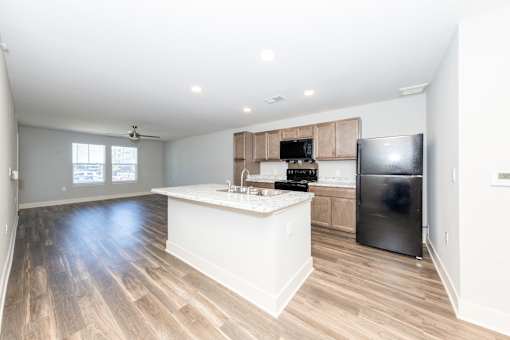 A kitchen with a black refrigerator and wooden floors.