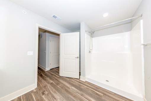 A white bathroom with a walk-in shower and a white door.