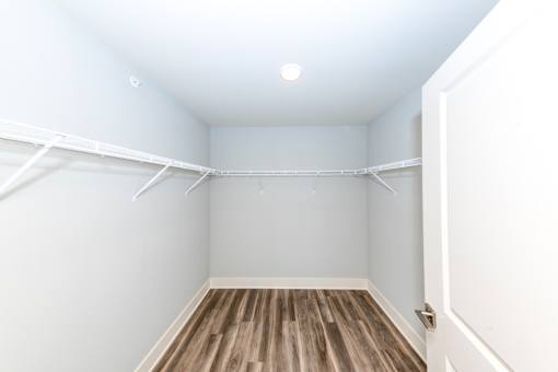 A white closet with a wooden floor and a door.