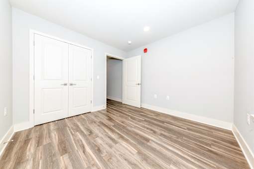 A room with white walls and wood flooring with a red light on the wall.