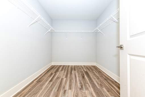 A room with a white door and a white ceiling with a wood floor.
