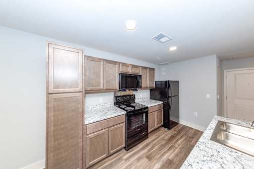 A kitchen with wooden cabinets and a black fridge.
