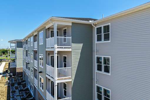 A grey apartment building with balconies and multiple windows.