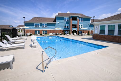 A pool with  lounge chairs and apartment buildings in the background