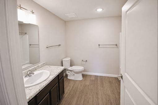 A white bathroom with a toilet, sink, and mirror.