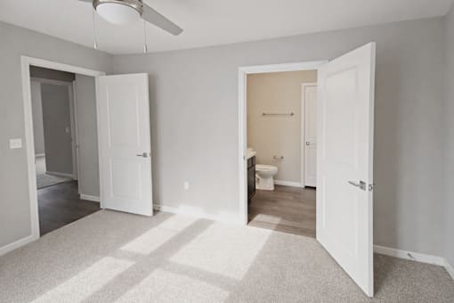 A room with a carpeted floor and a ceiling fan.