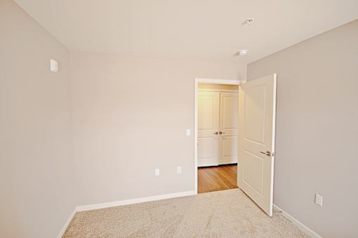 A room with a white door and a carpet on the floor.