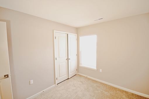A room with a carpeted floor and a door leading to another room.