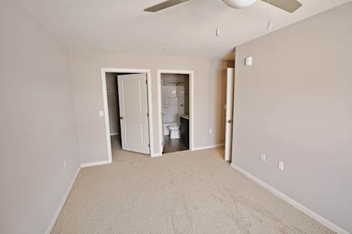 A room with a carpeted floor and a ceiling fan.