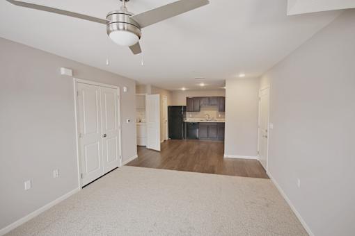 A spacious living room with a ceiling fan and a beige carpet.