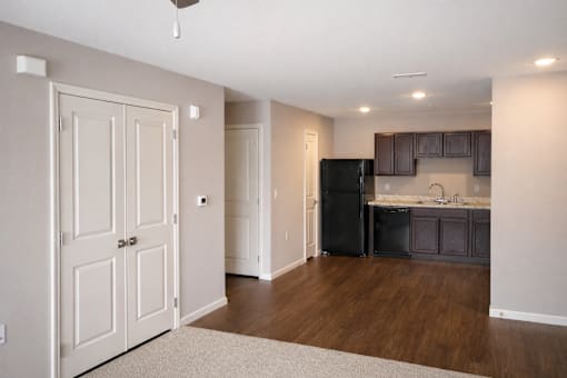 A kitchen with a black fridge and brown cabinets.