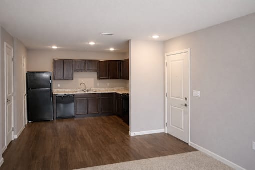 A kitchen with a black fridge and brown cabinets.