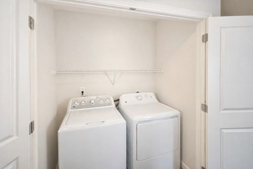Two white washing machines in a small laundry room.