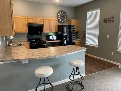 A kitchen with a granite countertop and two white stools.
