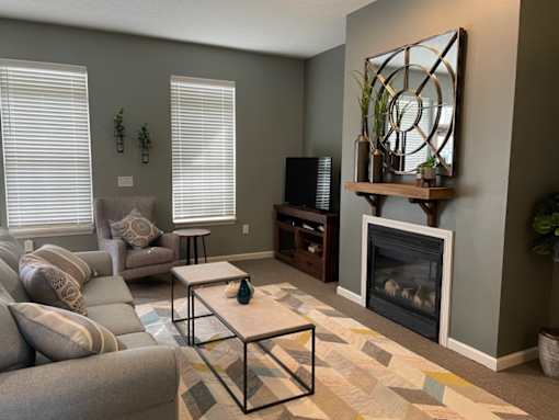 A living room with a grey couch, a white coffee table, and a fireplace.