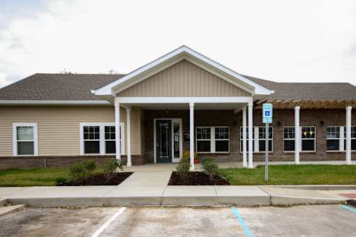 A building with a brown roof and a parking lot in front.