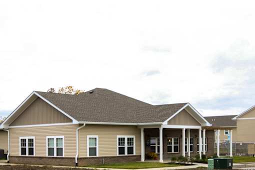 A house with a brown roof and beige siding with white trim.