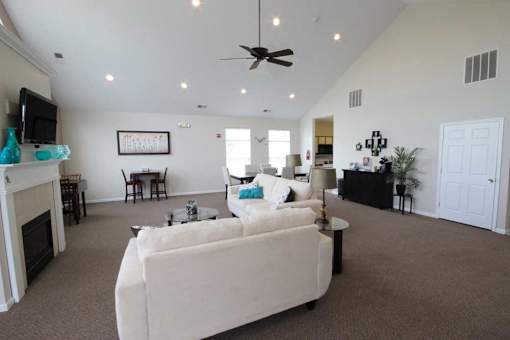 community living room with a white couch and a ceiling fan at canterbury apartments in kalamazoo, mi