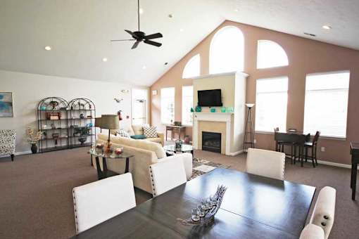 Community living room with a dining table and a fireplace at canterbury apartments in kalamazoo, mi