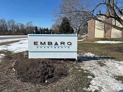 A sign for Embark Apartments sits in a mound of dirt.