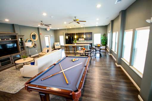 A pool table is in the middle of a room with a television and a couch.