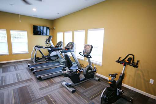 A room with a yellow wall and a treadmill.