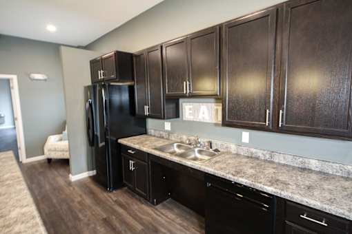 A kitchen with dark brown cabinets and a granite countertop.