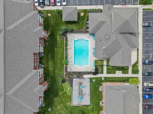A bird's eye view of a residential area with houses, a swimming pool, and a parking lot.