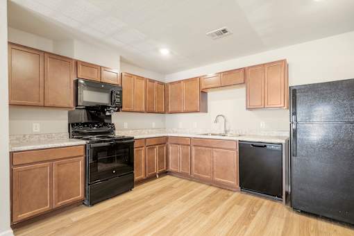 A kitchen with wooden cabinets and black appliances.