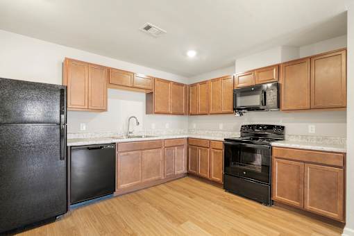 A kitchen with wooden cabinets and black appliances.