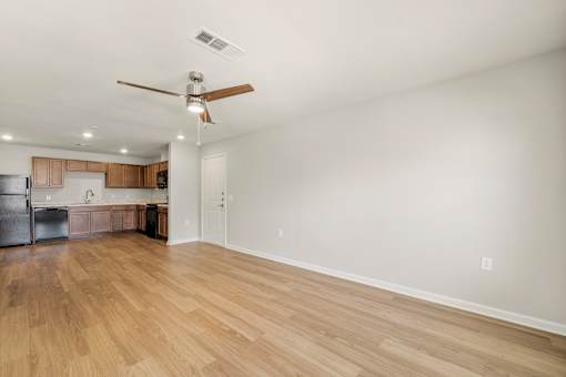 A room with a ceiling fan and wooden flooring.
