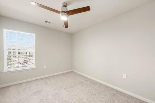 A room with a ceiling fan and a window with blinds.