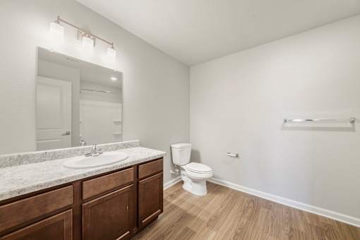 A white bathroom with a toilet, sink, and mirror.