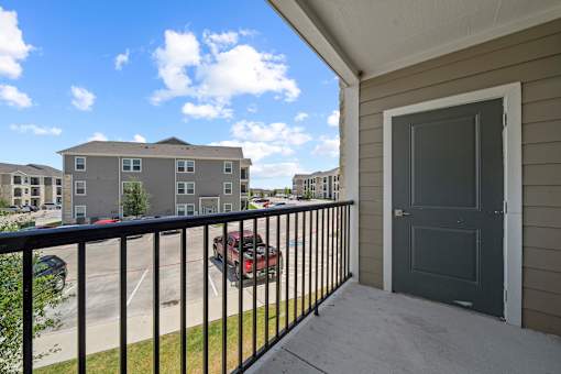 A balcony with a black railing and a grey door.