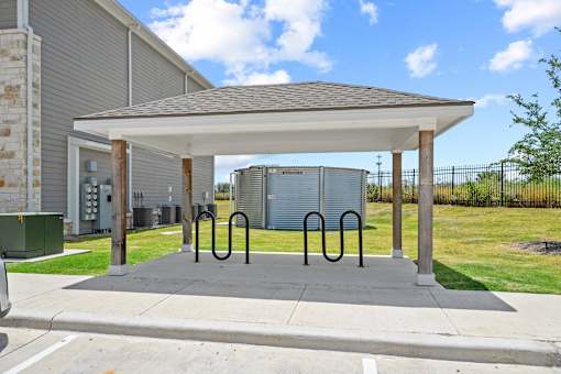 A covered parking area with a concrete floor and a metal railing.