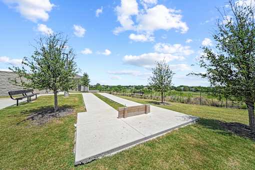 A park with a bench, a tree, and a concrete path.