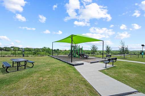 A playground with a green canopy and a slide.