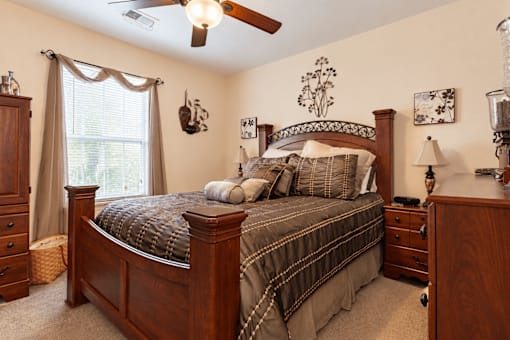 A bedroom with a bed, dresser, and ceiling fan.