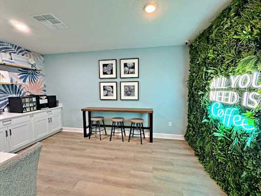A room with a green wall and a neon sign that says "All you need is coffee".