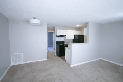 an empty living room with a kitchen in the background at Frankfort Place apartments in Frankfort, Indiana